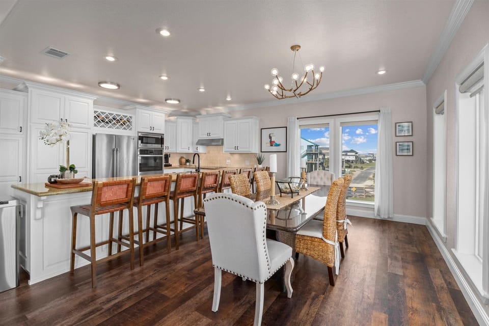 Open dining and kitchen area with stylish lighting and seating for large groups in this luxury beach home.