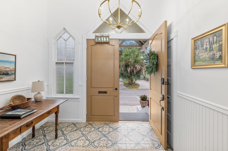 Bright, elegant entryway with a high ceiling and a door opening to the outdoors.