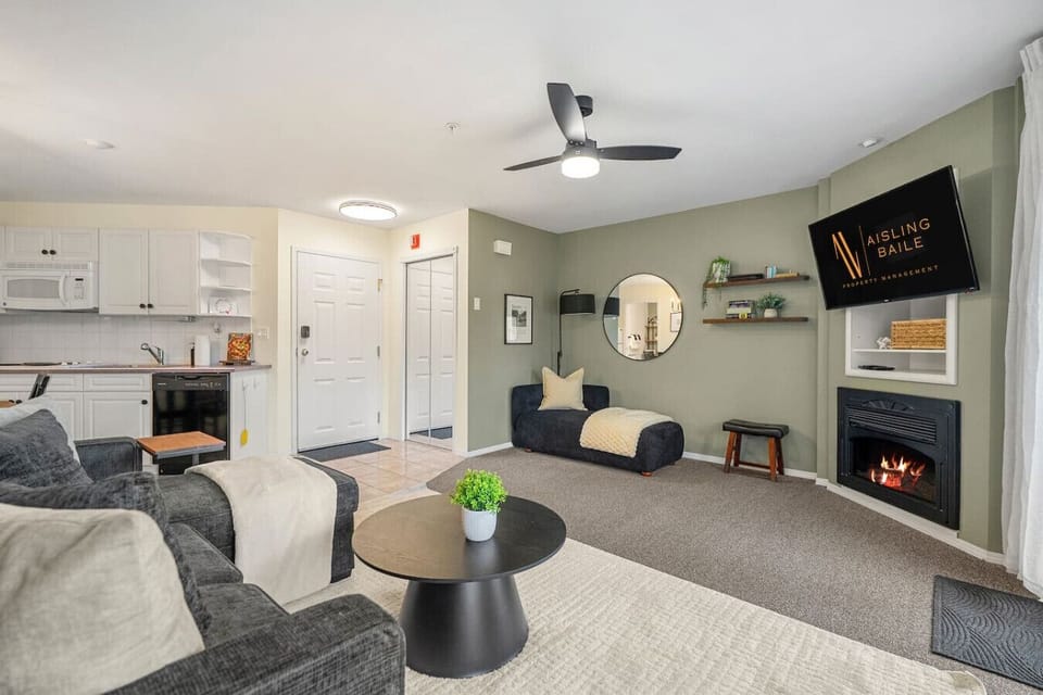 Living room with a gas-lit fireplace, smart TV, board games, walkout access to the balcony and a luxurious couch with a sleeper sofa (all bedding provided.)
