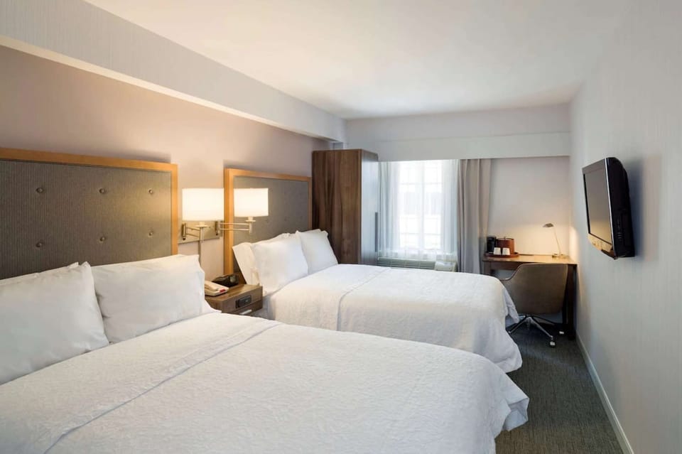 Double-bed guest room with TV, work desk, and natural light