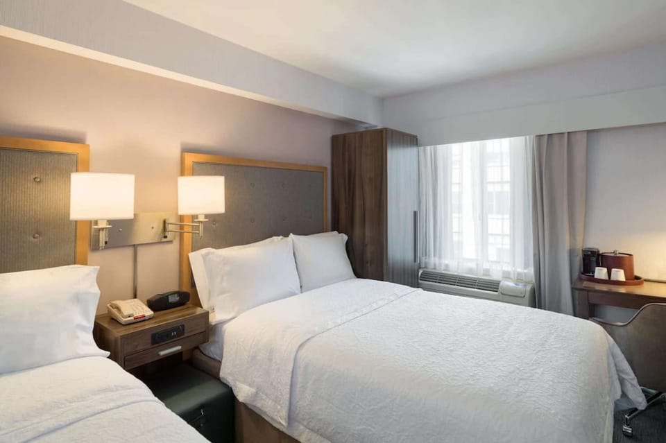 Cozy room with two double beds, soft lighting, and desk area