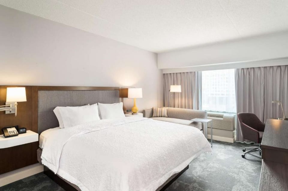 King bed room with sofa, desk, lamps, and large window view