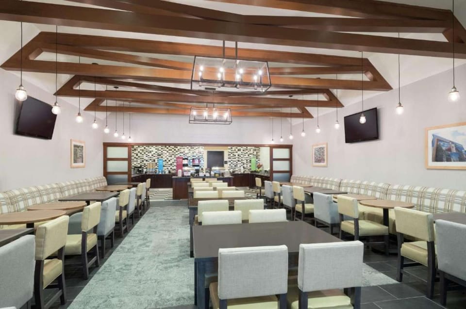 Dining room with wooden beams, TV screens, and comfy chairs
