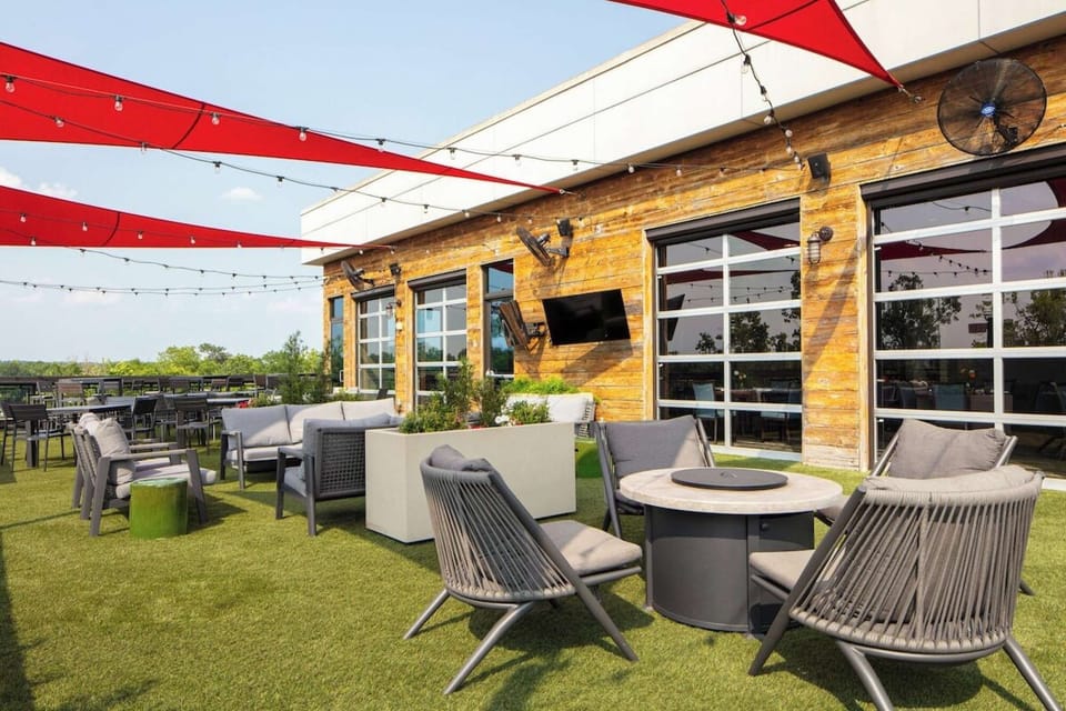 Rooftop patio with red shades, chairs, and green turf seating area