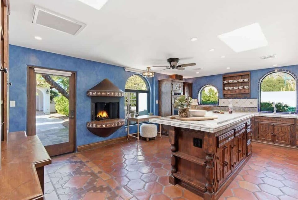 Fully equipped kitchen with stainless steel appliances, a sleek kitchen island, ample counter space, and a gas fireplace.
