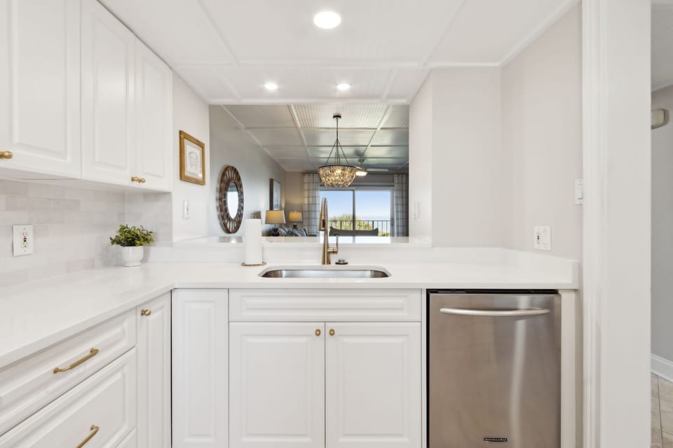 Luxury Remodeled Kitchen with Stainless Steel Appliances, Stunning White Cabinetry, Quartz Countertops, Gold Finishes and a Trendy Backsplash