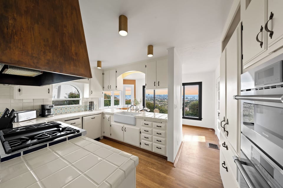 Tile countertops and farmhouse sink overlook sunset views through arched windows