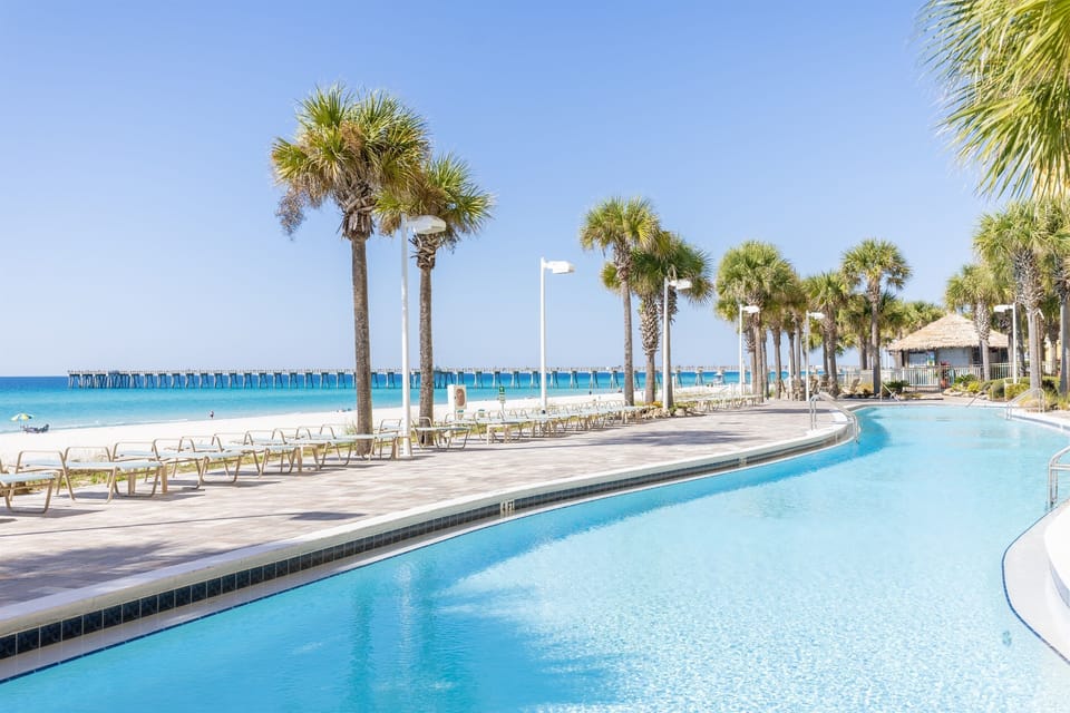 Stunning beachfront pool curves along pristine white sand and swaying palms, with crystal-clear waters just steps from your tropical retreat.
