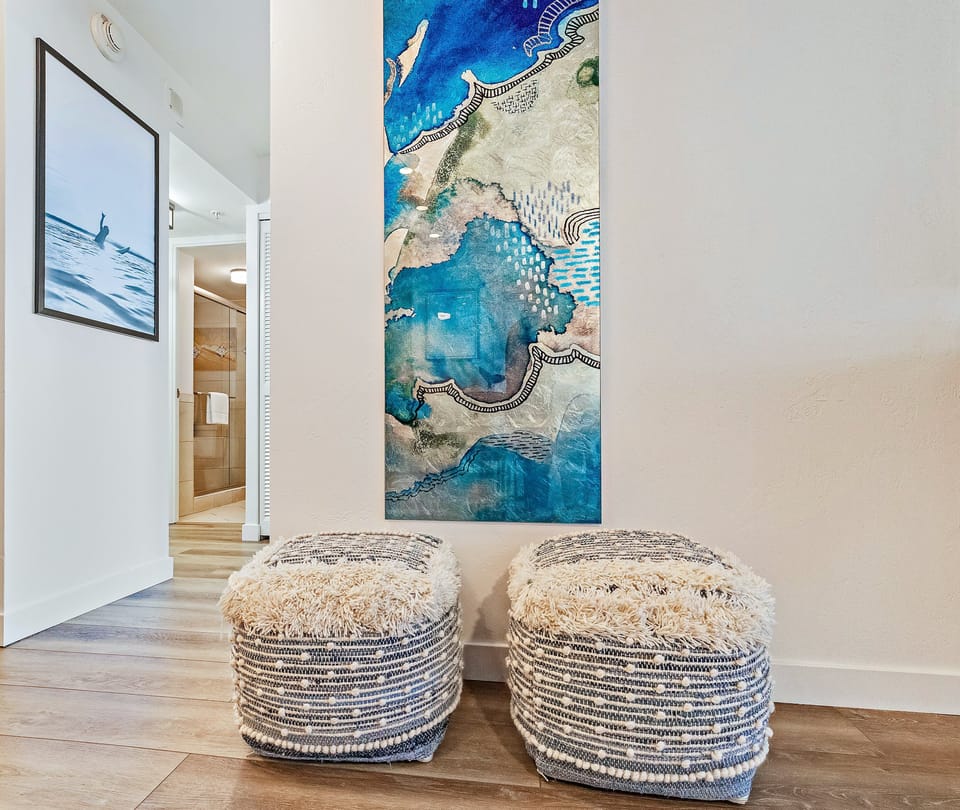 Entryway detail with textured ottomans and a striking blue abstract art piece.