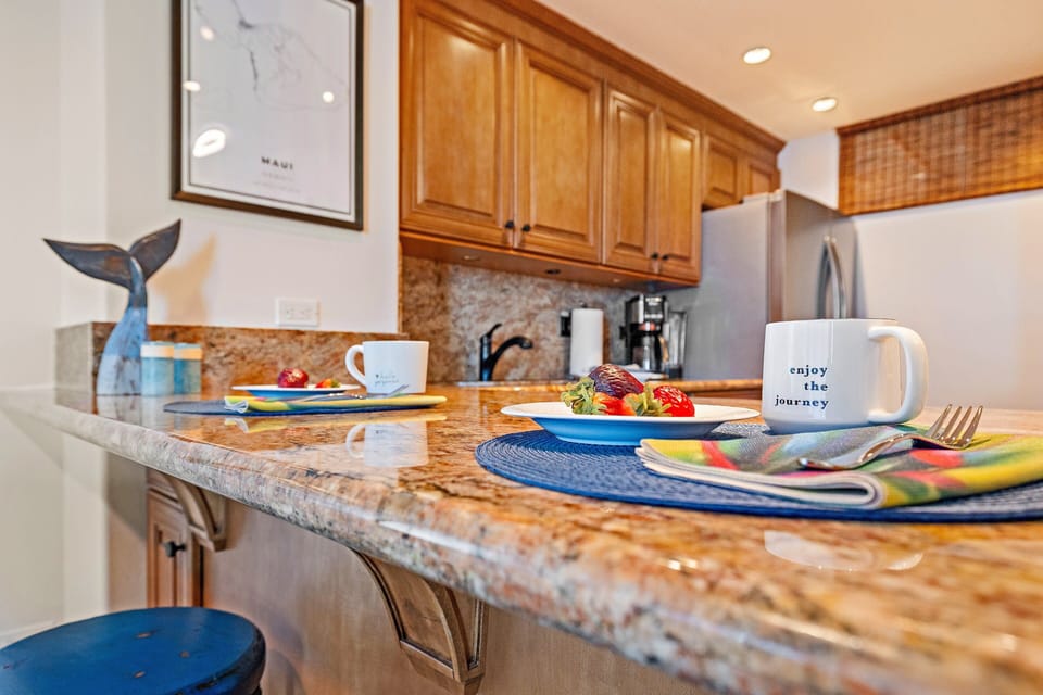 Kitchen counter with granite surface, warm wood cabinetry, and breakfast setup for two.