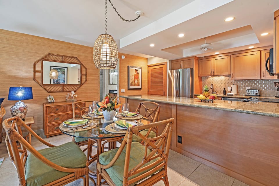 Enjoy a cozy dining area with tropical-inspired seating and a view into the fully equipped kitchen.