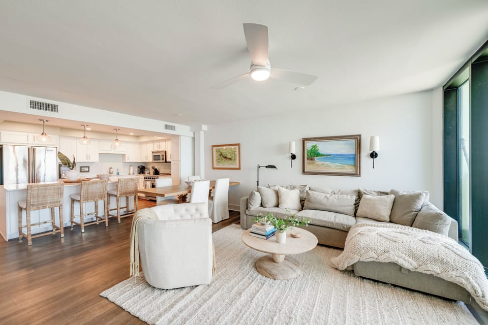 Relax in your spacious living room with plush seating, ocean artwork, and an open kitchen perfect for entertaining.