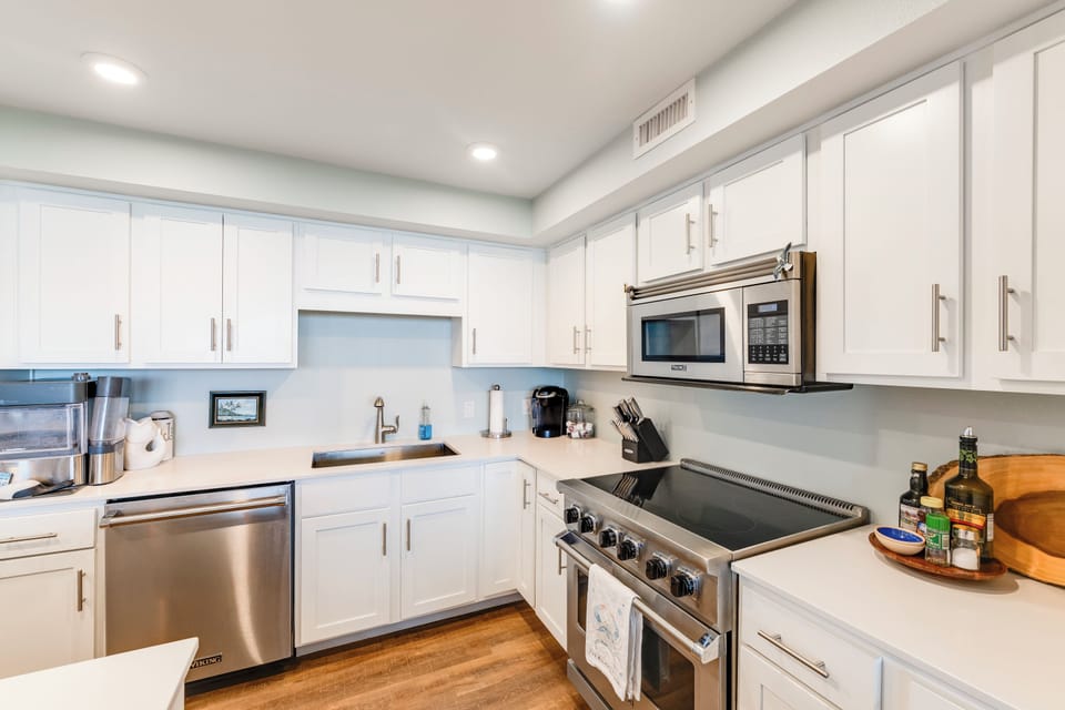 Your fully equipped modern kitchen features pristine white cabinets, stainless steel appliances, and gleaming countertops—perfect for preparing memorable meals together.