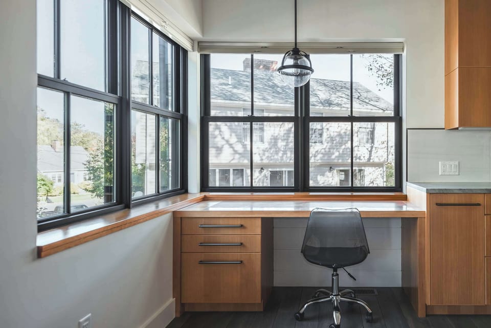 Home office nook with picture windows and built-in desk workspace