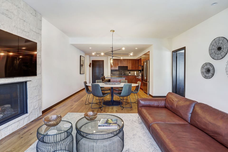 Inviting lounge with stone-framed fireplace, twin coffee tables, and balcony access for mountain sunsets.