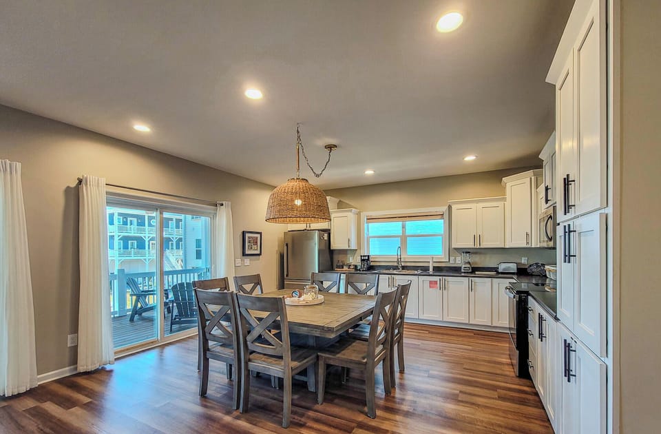 Gather around your spacious dining table where warm wood floors and modern white cabinets create the perfect space for memorable meals together.