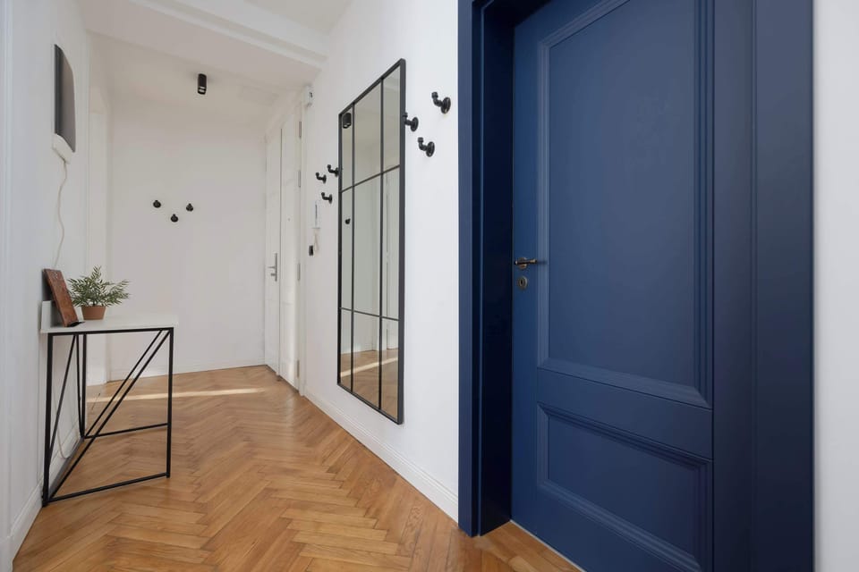 A hallway with light wood floors and a deep blue door. The minimalist design looks elegant and contemporary.