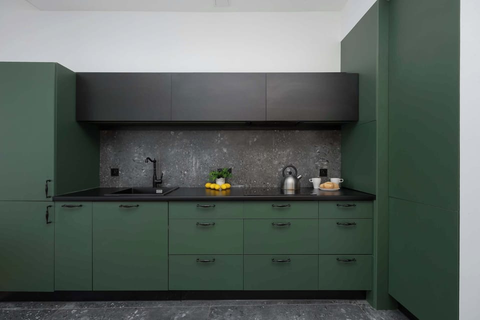 A close-up of the green kitchen with dark accents and subtle lighting. The design feels modern and clean.