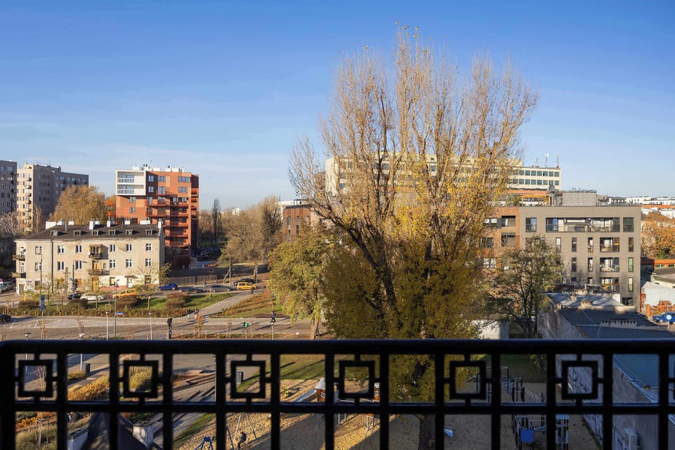 Another balcony view highlighting autumn-colored trees and nearby structures. The bright blue sky adds to the pleasant scenery.