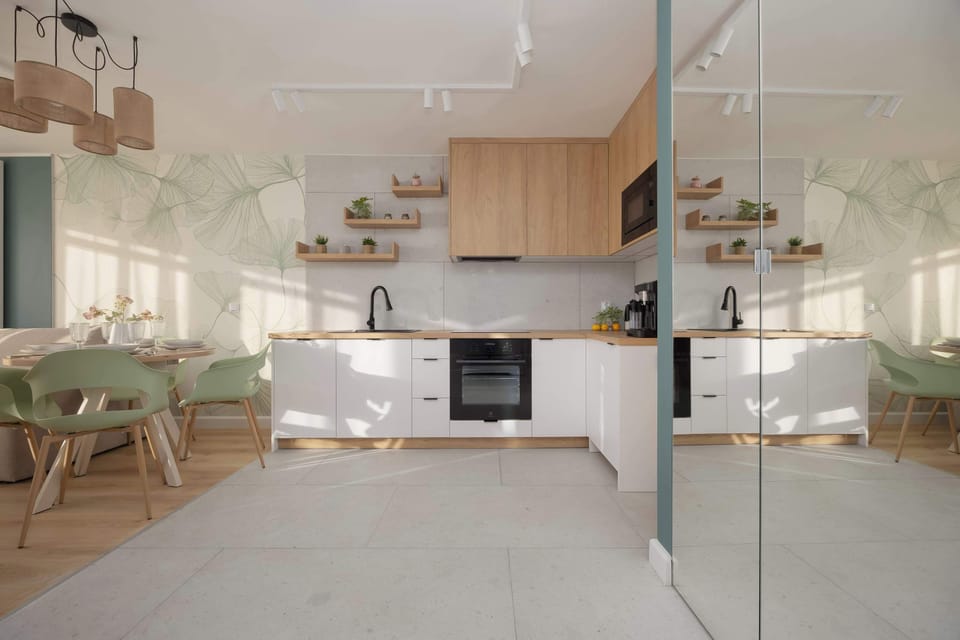 A sleek open-concept kitchen and dining area with light wood tones and minimalistic décor. The reflective surfaces enhance the spacious feel.