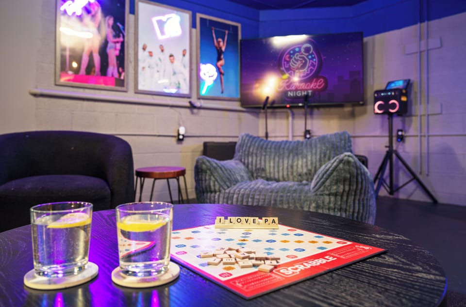 Stylish game lounge with neon lighting, TV, music, and cozy seating