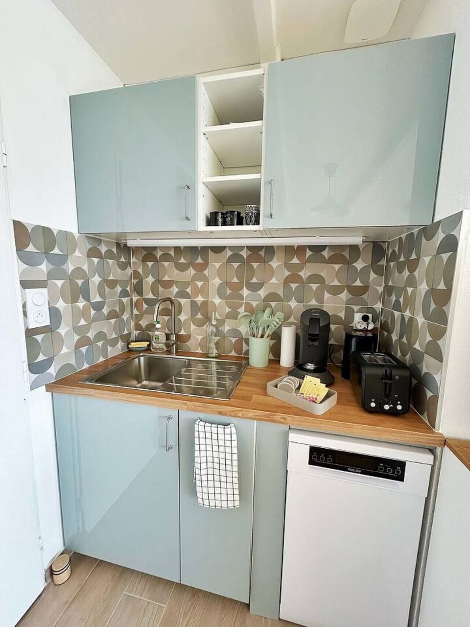 Kitchenette entièrement équipée – plan de travail bois, machine à café Nespresso, grille-pain, évier inox et crédence carreaux rétro. Tout le nécessaire pour cuisiner avec plaisir à Leucate.
