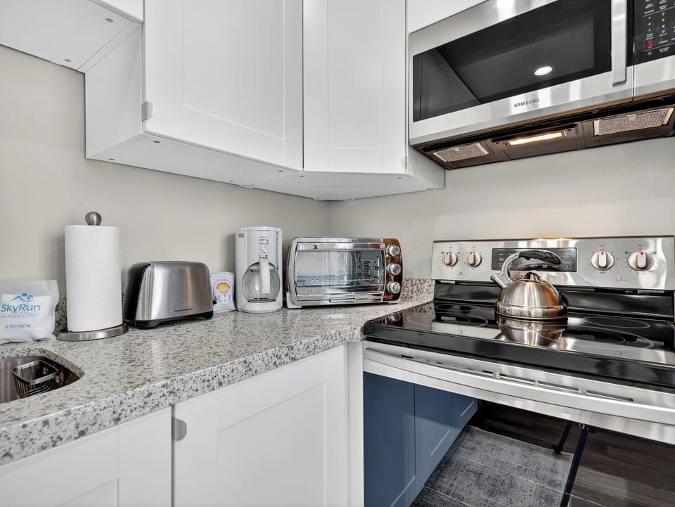 Your fully equipped kitchen awaits with gleaming granite countertops and modern stainless steel appliances. Brew your morning coffee, toast fresh bagels, or whip up a home-cooked meal in this bright, pristine space designed for your comfort.
