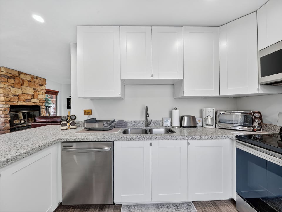 Your fully equipped kitchen awaits with granite countertops, stainless steel appliances, and everything you need to prepare meals. The cozy stone fireplace creates a warm, inviting atmosphere for your stay.