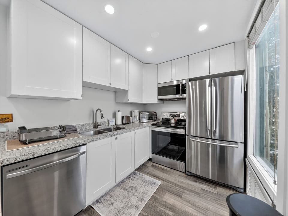 Step into your sleek, fully-equipped kitchen where culinary adventures await! Gleaming stainless steel appliances and pristine white cabinetry create the perfect backdrop for morning coffee or home-cooked meals during your stay.