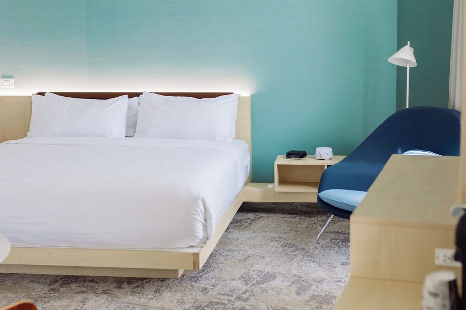 Soft tones, crisp linens, and a sweeping city view define this refined king bedroom at Hotel Eleo.