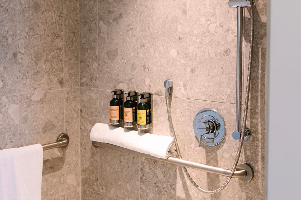 Step into luxury with this ADA-accessible roll-in shower at Hotel Eleo, where modernity meets comfort just steps from the University of Florida.