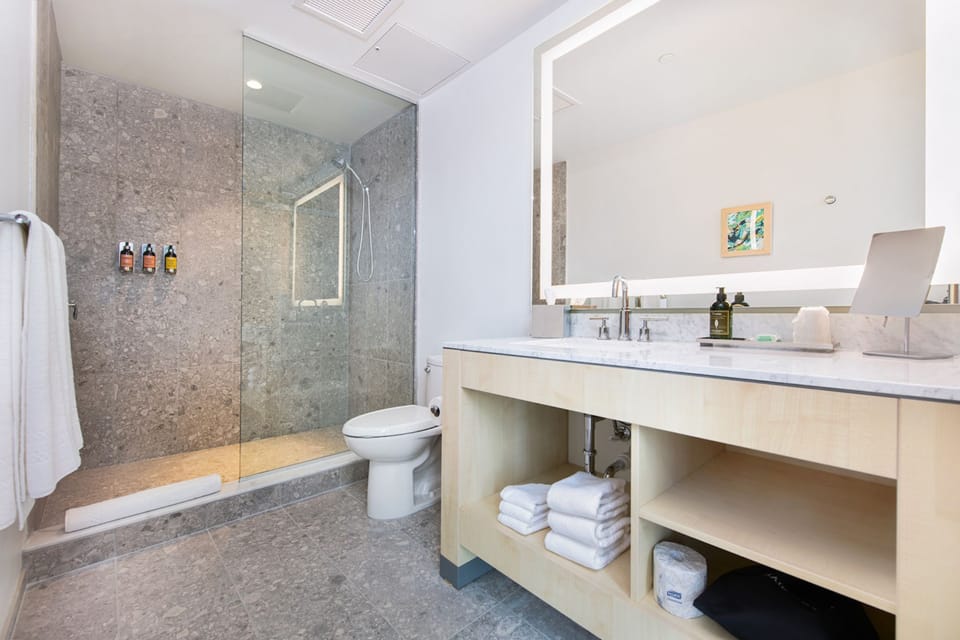 Experience modern comfort in the spacious City View Two Queen Guestroom, featuring a stylish bathroom with sleek marble finishes and luxury amenities that enhance your stay.