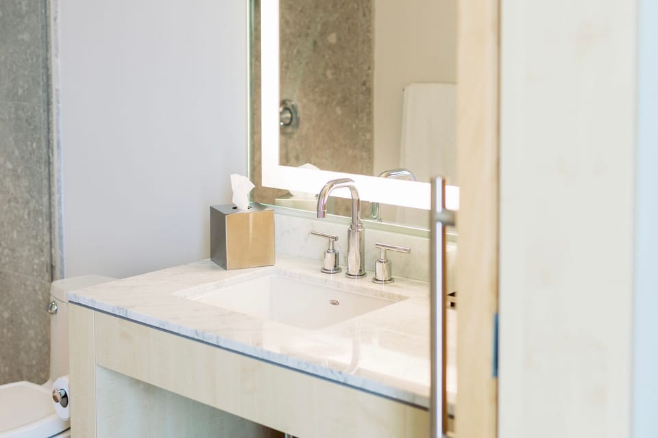 The elegantly designed bathroom offers a contemporary sink and refined fixtures, ensuring a relaxing and stylish experience in your City View Two Queen Guestroom at Hotel Eleo.