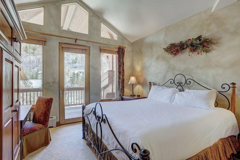 Primary bedroom featuring a king bed, soft lighting, and balcony access with alpine views.