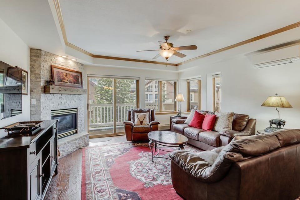 The cozy living room features a warm fireplace and large windows that invite natural light, creating an inviting space to relax.