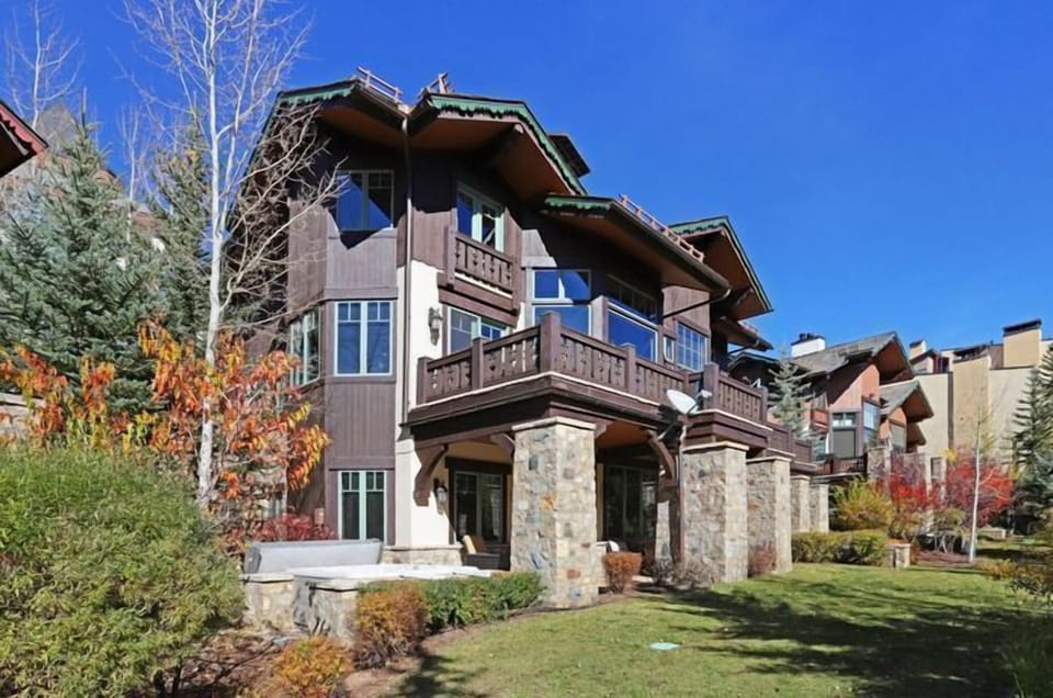 Embrace the vibrant autumn scenery surrounding this exquisite townhome, highlighted by rich stone accents and a spacious outdoor area ideal for enjoying the breathtaking views.