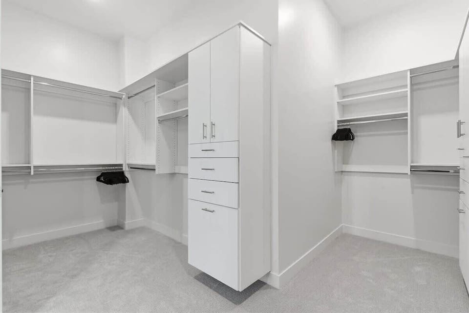 Primary bedroom features a king bed, smart TV, large dresser, walk-in closet, soft wood tones, and an en-suite bathroom.