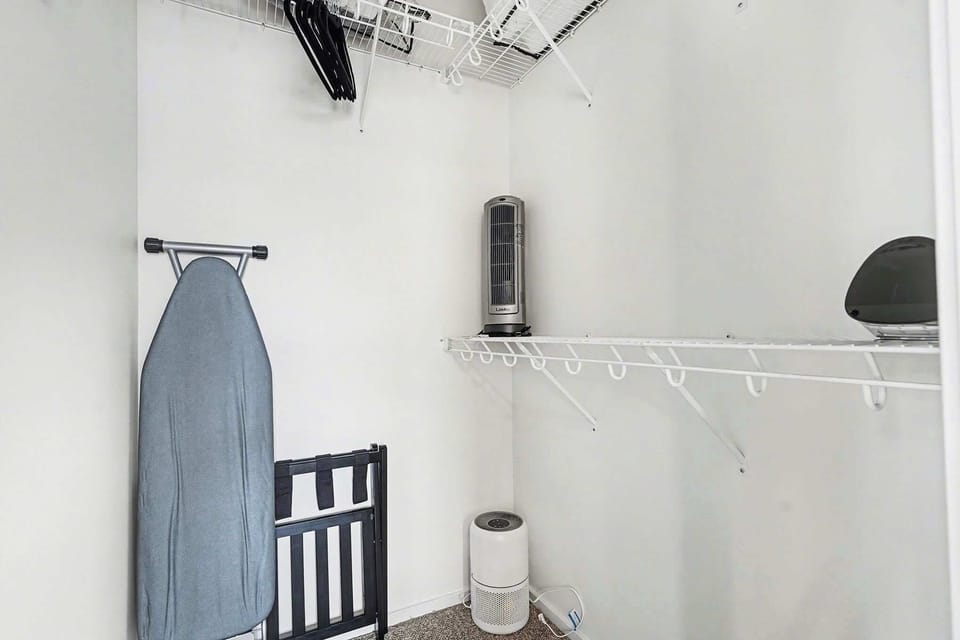 The third-floor primary suite offers a peaceful retreat with a king-size bed, private ensuite bathroom, blackout curtains, ceiling fan, and a spacious walk-in closet complete with luggage rack and hangers for added convenience.