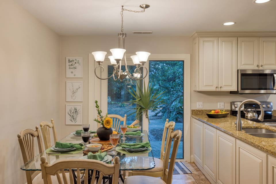 Multiple dining areas are set for a cozy meal, featuring warm lighting and garden views.