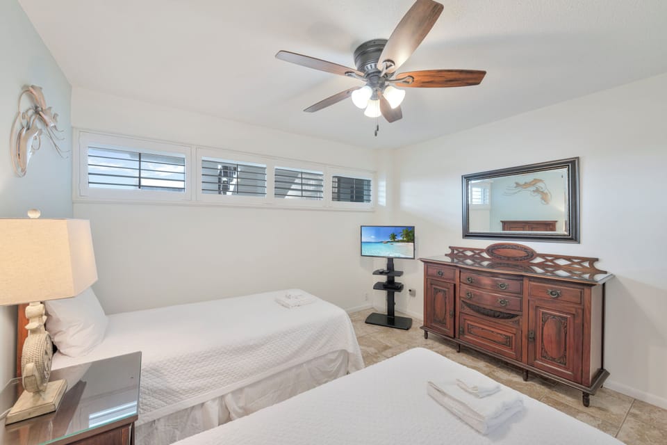Relax in your peaceful bedroom with comfortable twin beds, tropical TV viewing, and gentle ceiling fan keeping you cool.