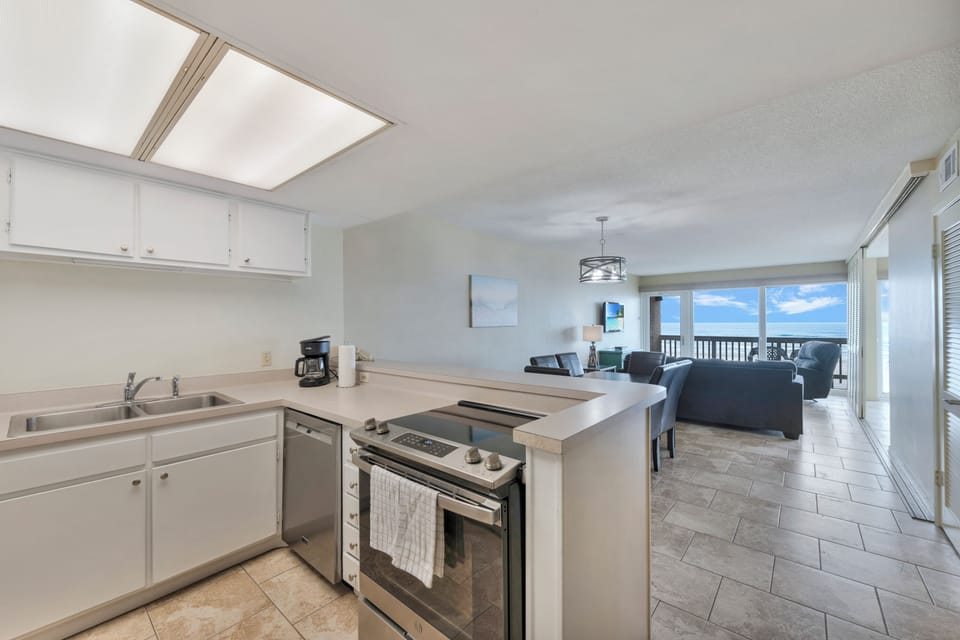 Your fully equipped kitchen flows seamlessly into the living area, where stunning sea views await through expansive windows—perfect for cooking while enjoying breathtaking sunsets.