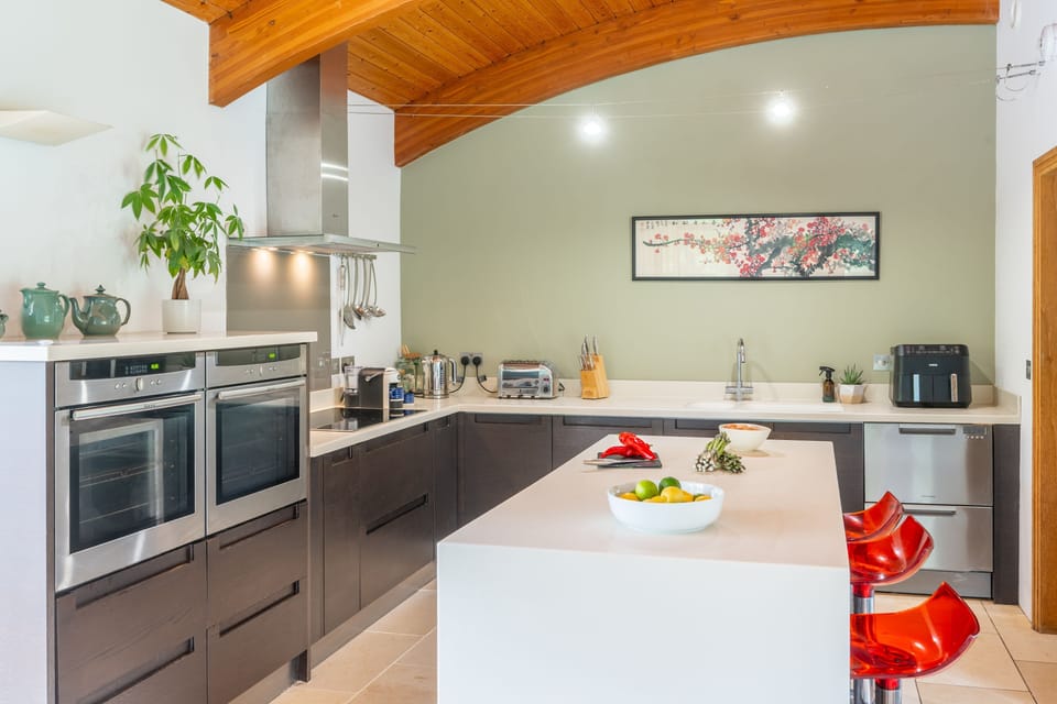 First floor: Kitchen area with double electric ovens and induction hob, microwave, fridge (with double sliding drawers), dishwasher, air fryer and Lavazzo coffee machine and sit up island with three stools