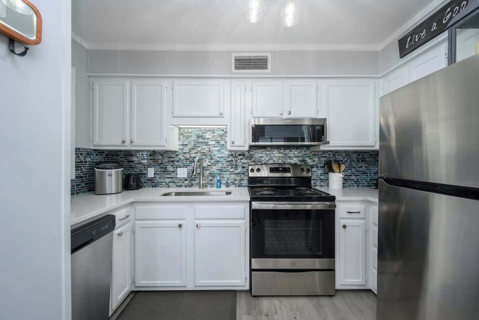 Updated with sleek white cabinetry, stainless steel appliances, and a beautiful blue-tiled backsplash that reflects the home’s seaside theme.