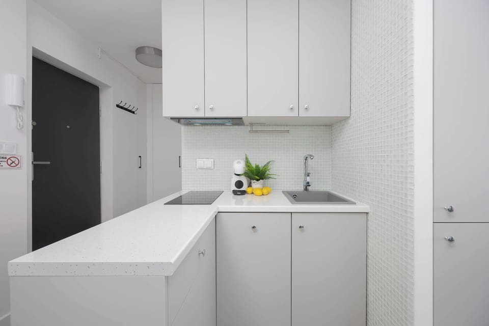 The minimalist white kitchenette makes meal preparation comfortable and brings a sense of cleanliness and lightness.