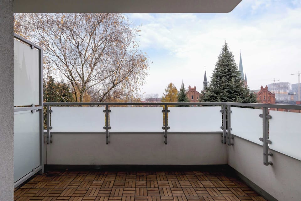A balcony with metal railing and a wooden floor. It offers a small outdoor area to relax.