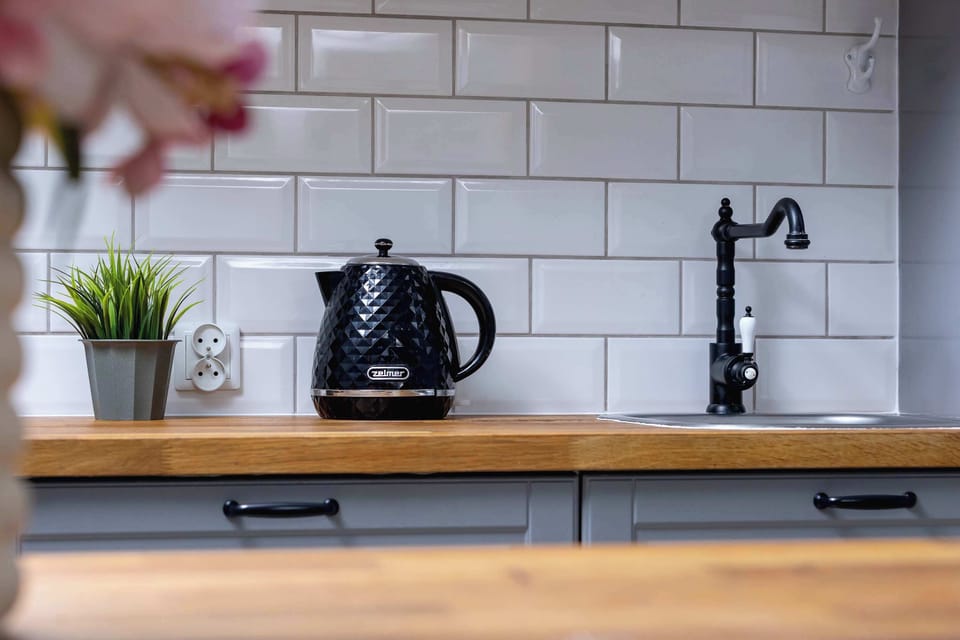 Close-up of a kitchen countertop with a kettle and sink. White subway tiles add a clean and modern touch.