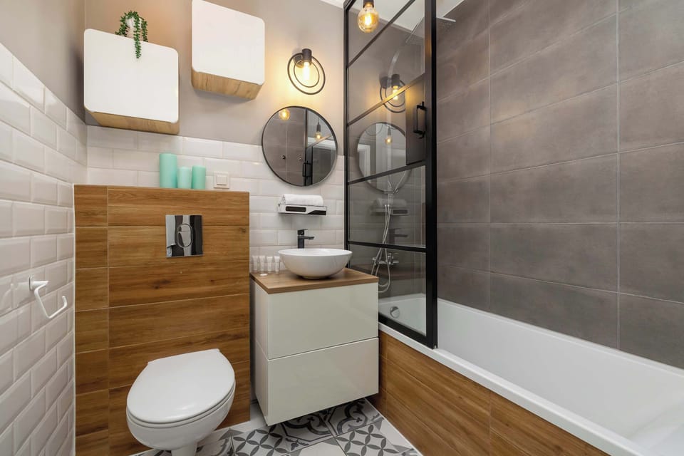 A bathroom with a modern design, featuring a bathtub, wooden accents, and tiled walls. The space is well-lit and functional.