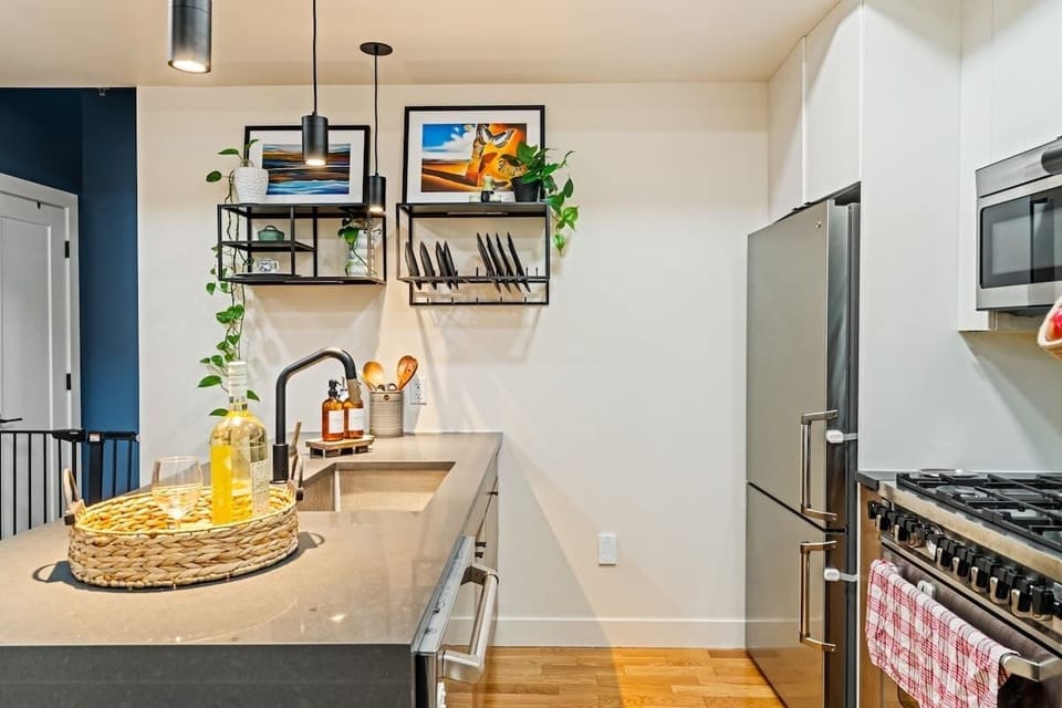 Thoughtful touches like the hanging baskets, framed art, and a welcome tray with wine and glasses make this kitchen as inviting as it is functional.