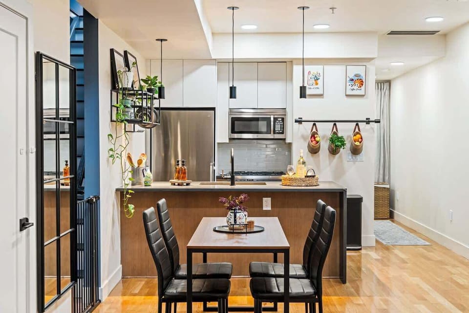 A fully equipped modern kitchen featuring stainless-steel appliances, open shelving, and stylish black fixtures. Perfect for preparing meals or enjoying a glass of wine while cooking.