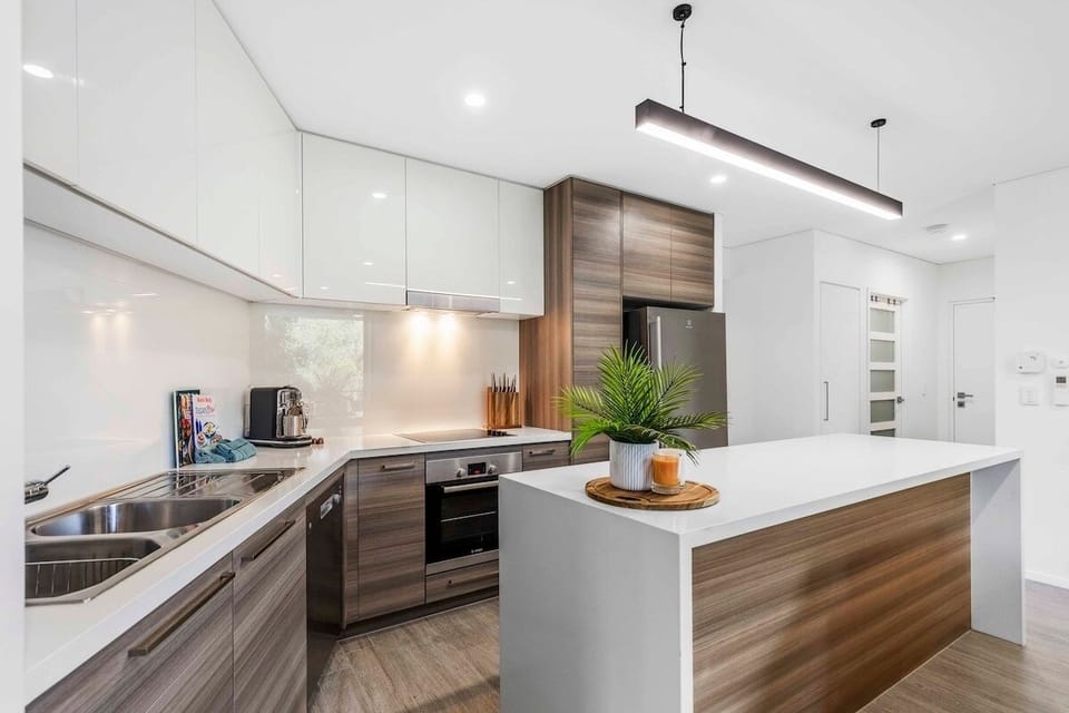 Full kitchen with island, oven, cooktop, dishwasher and fridge.